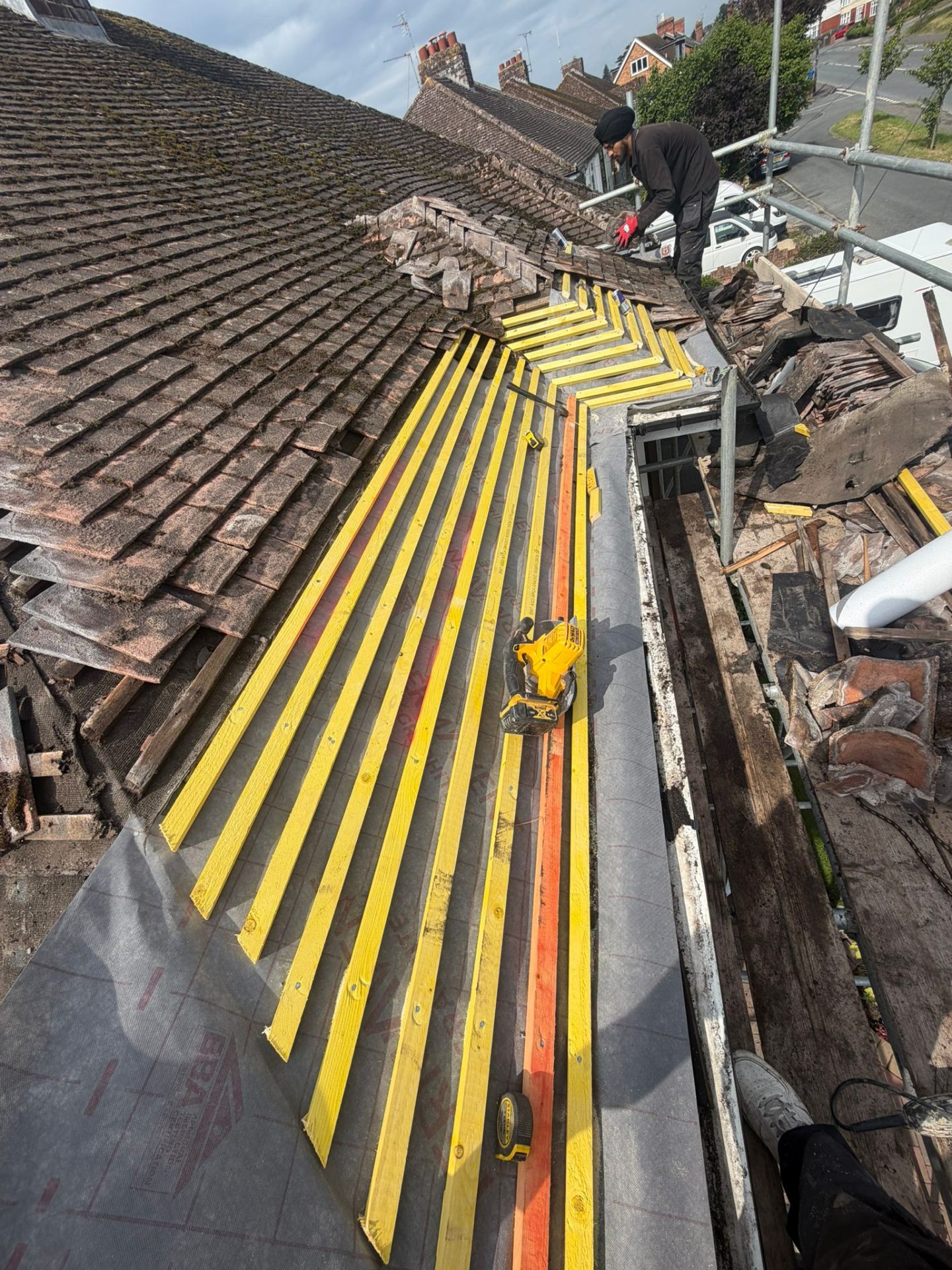 Pitched roof stripped back showing yellow treated battens and breathable membrane mid-strip