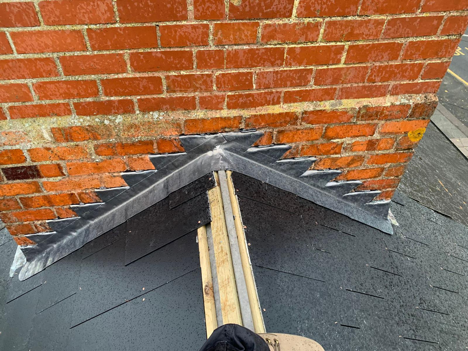 Chimney Repairs & Repointing in Worcester — New lead flashing dressed into brickwork where a pitched roof meets a chimney stack